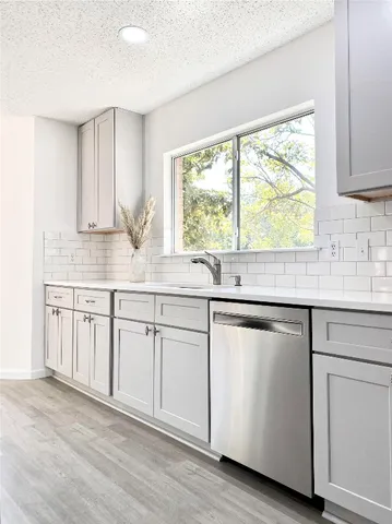 a kitchen with cabinets stainless steel appliances and wooden floor