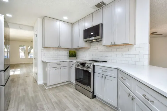 a kitchen with stainless steel appliances a stove microwave and sink