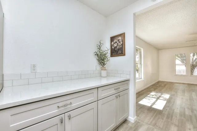 a kitchen with white cabinets and window