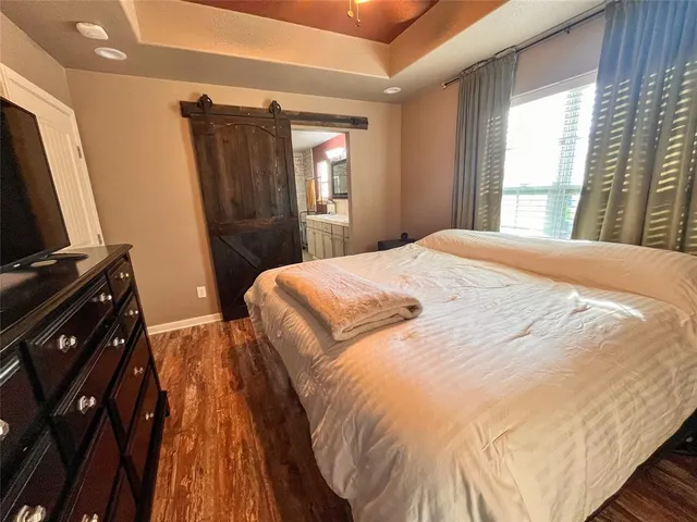 a bedroom with a bed and a flat tv screen next to a window