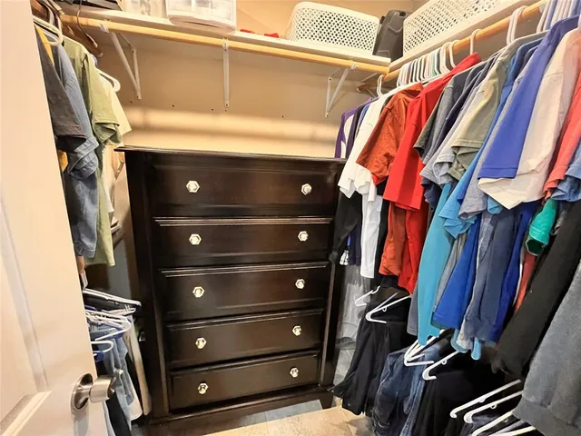 a view of walk in closet with clothes and shoes