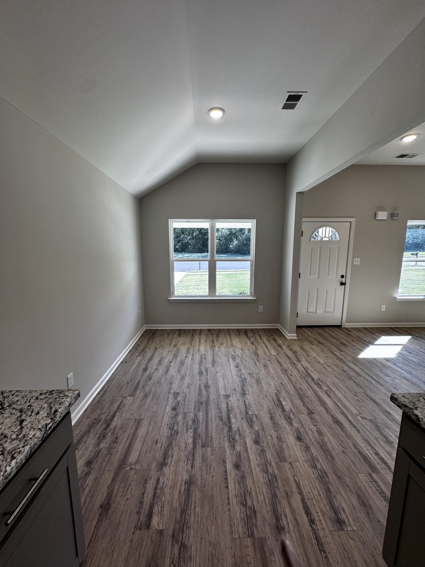 Unfurnished living room featuring lofted ceiling and dark wood-style floors
