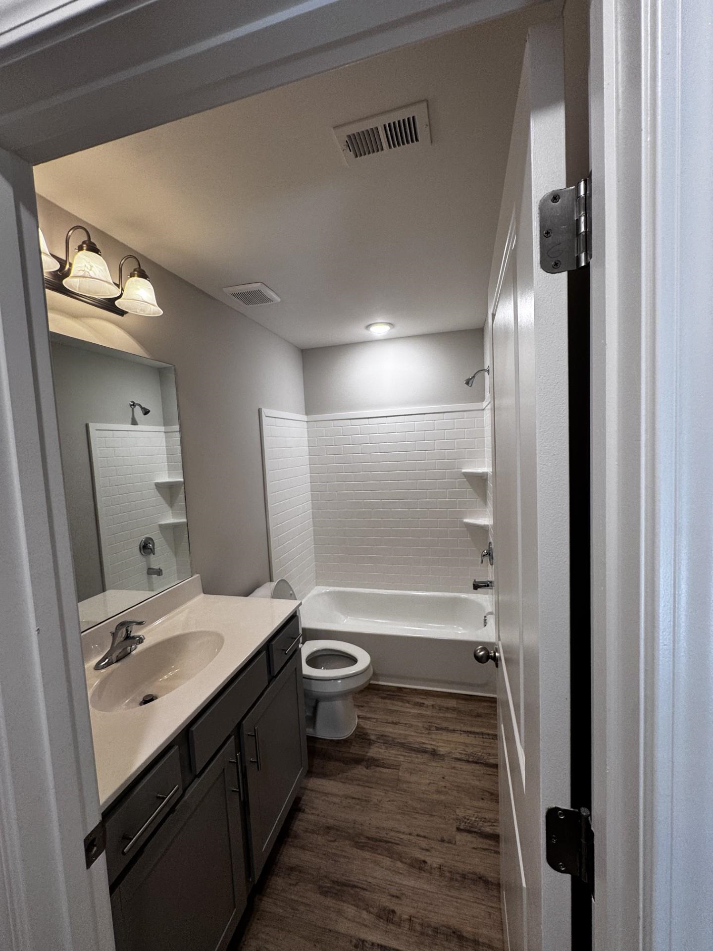 Full bathroom with vanity, shower / bathtub combination, and dark wood-style floors