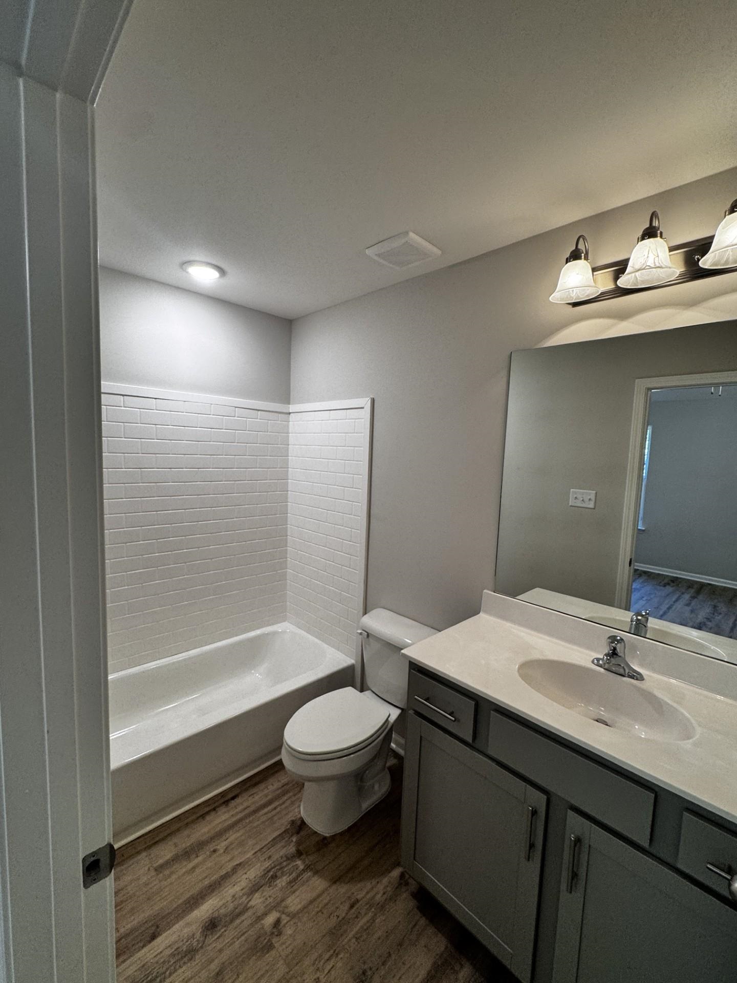 Full bath with dark wood-style flooring, vanity, and bathtub / shower combination