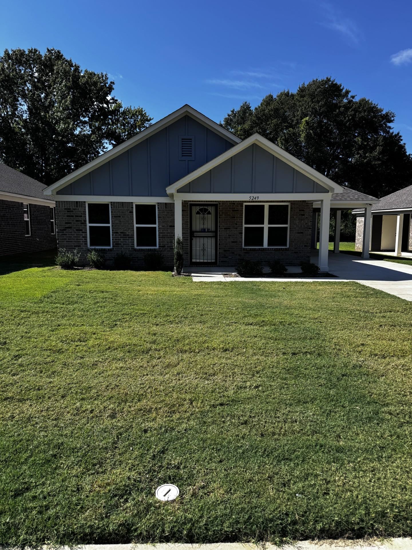 View of front facade featuring board and batten siding, a front lawn, and brick siding