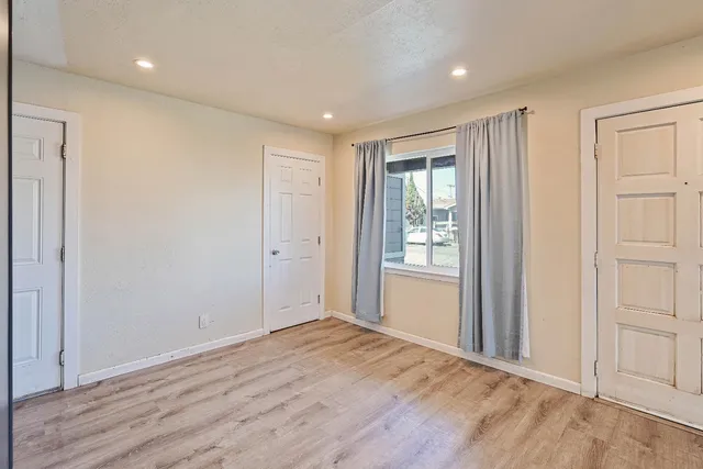 a view of an empty room with wooden floor and a window