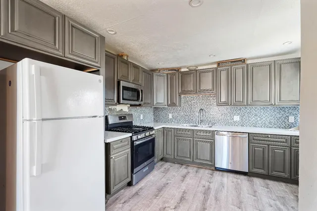 a kitchen with kitchen island granite countertop stainless steel appliances and wooden cabinets