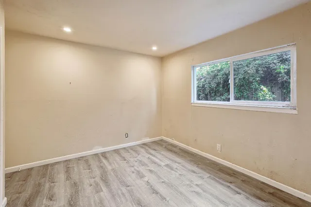 an empty room with wooden floor and windows