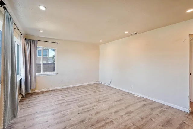 an empty room with wooden floor and windows