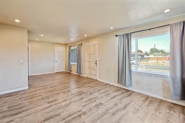 a view of an empty room with wooden floor and a window