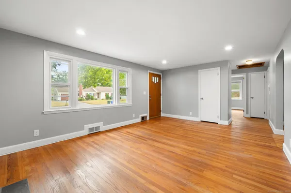 a view of an empty room with wooden floor and a window