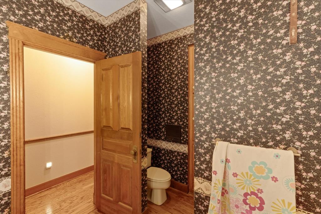 2717 Clear Lake Road Weatherford, TX 76087 - Photo 23 of 40 Interior space featuring wood-finish flooring, a traditional paneled wood door with fluted trim, and floral wallpaper with a complementary border