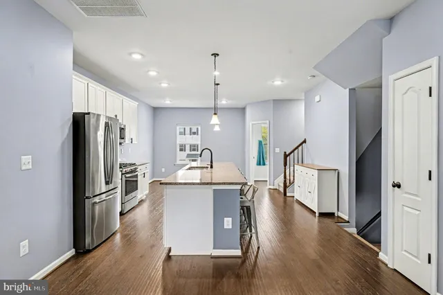 a kitchen with kitchen island a refrigerator a stove a sink and a oven with wooden floor