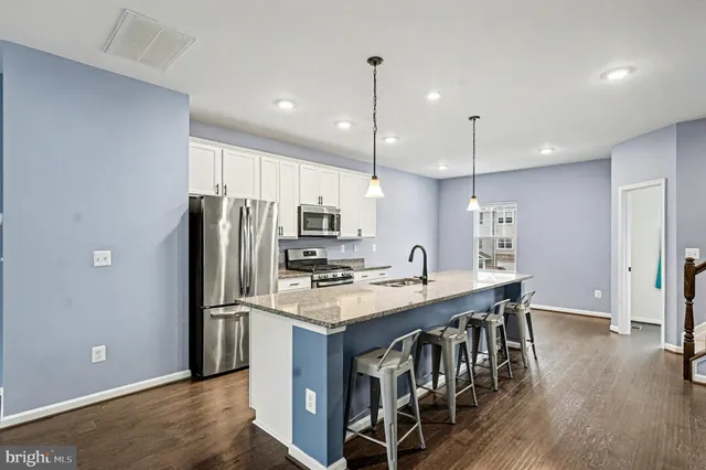 a kitchen with stainless steel appliances granite countertop a refrigerator a sink dishwasher a stove and a oven with wooden floor