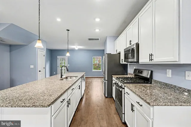 a kitchen with stainless steel appliances granite countertop a kitchen island a stove a refrigerator and a sink