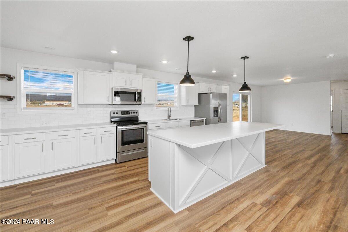 25341 North Mitchell Road Paulden, AZ 86334 - Photo 4 of 17 a kitchen with stainless steel appliances kitchen island granite countertop a stove a sink and white cabinets with wooden floor