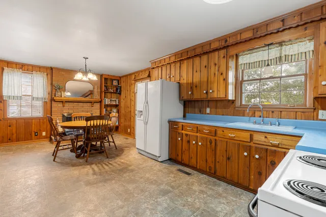 a kitchen with granite countertop wooden cabinets a dining table and chairs