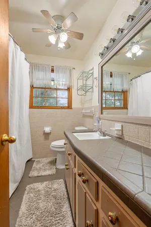a bathroom with a sink a toilet a mirror and shower