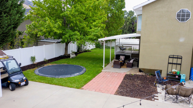 12169 Hidden Valley Road, Unit 44 Sandy, UT 84092 - Photo 44 of 49 Expansive green lawn, white privacy fencing, mature trees, multi-level deck with covered patio, and brick paver pathway