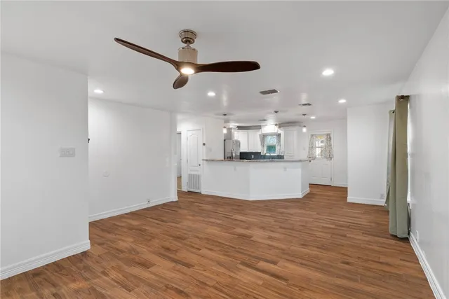 a view of kitchen and empty room with wooden floor