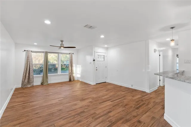 a view of an empty room with wooden floor and a window