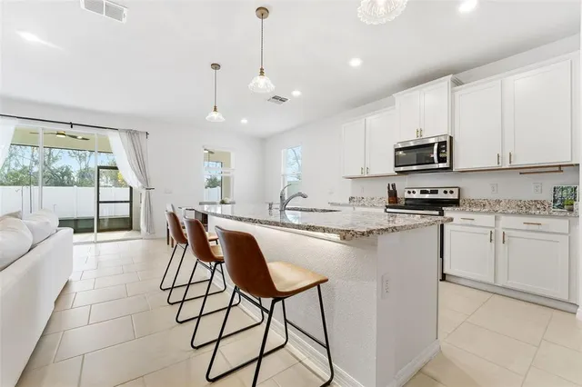 a kitchen with stainless steel appliances granite countertop a stove a sink a refrigerator a microwave oven with a dining table and chairs