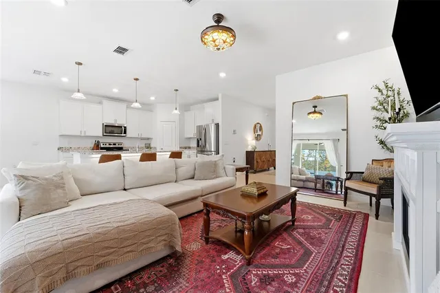 a living room with furniture a rug kitchen view and a table