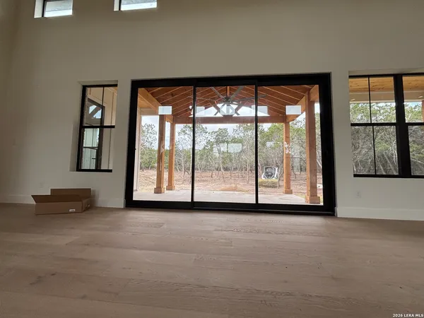 a view of an empty room with a floor to ceiling window and a flat screen tv