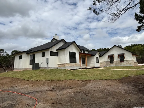 a white house with a big yard and large trees