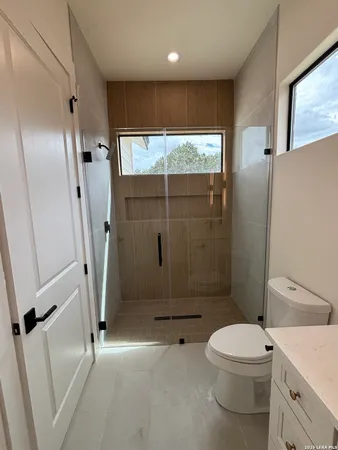 a bathroom with a toilet a sink a shower and mirror