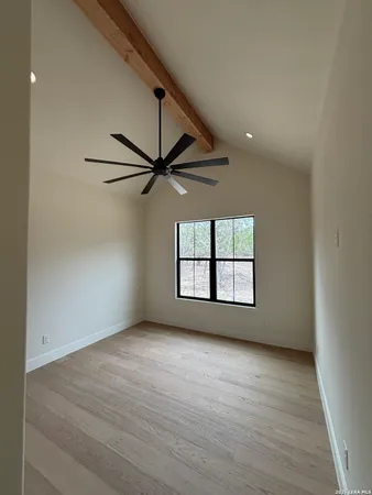 an empty room with wooden floor fan and windows
