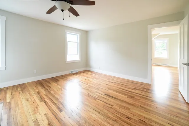 an empty room with wooden floor cabinet and windows