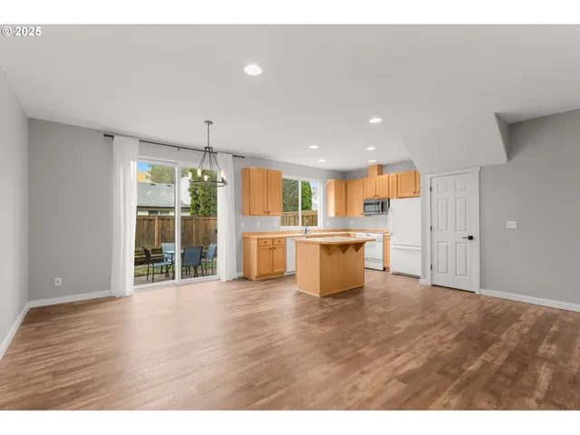 a open kitchen with kitchen island a sink dishwasher and a refrigerator with wooden floor
