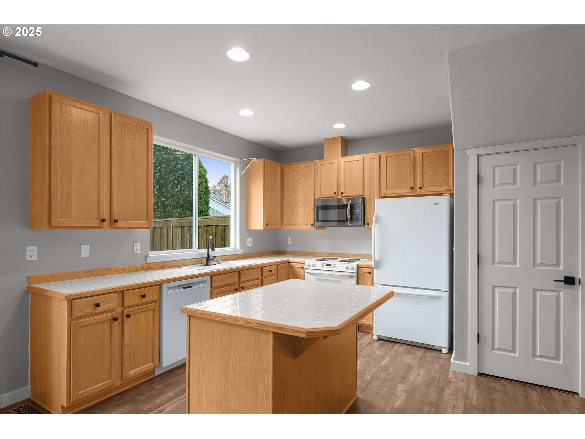 3255 Southwest 179th Terrace Beaverton, OR 97003 - Photo 13 of 38 a kitchen with stainless steel appliances a refrigerator a sink dishwasher a stove with white cabinets and wooden floor