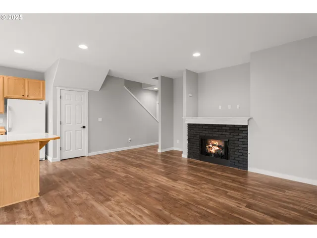 a view of an empty room with wooden floor fireplace and a window
