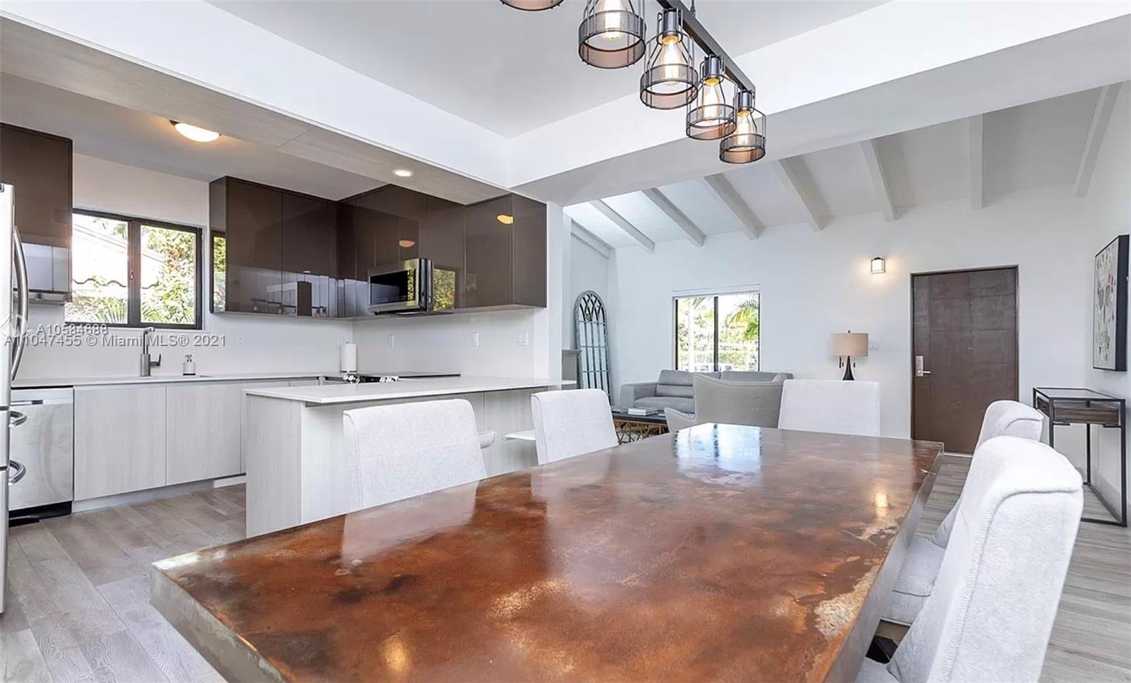 332 Southwest 20th Road Miami, FL 33129 - Photo 6 of 23 a kitchen with stainless steel appliances kitchen island granite countertop a sink dishwasher a dining table and chairs with wooden floor