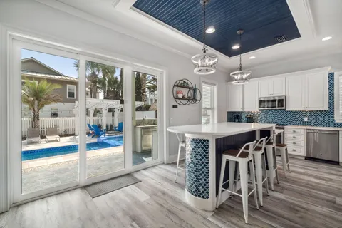 a kitchen with stainless steel appliances a dining table chairs refrigerator and cabinets