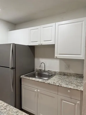 a kitchen with granite countertop a refrigerator sink and cabinets