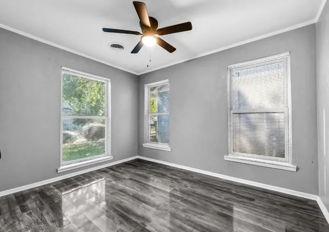 a view of an empty room with wooden floor and a window