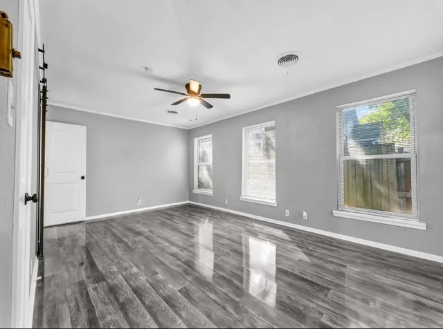 a view of an empty room with a window and wooden floor