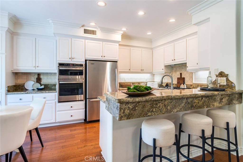2515 Lewis Drive Tustin, CA 92782 - Photo 10 of 34 a kitchen with granite countertop white cabinets and stainless steel appliances
