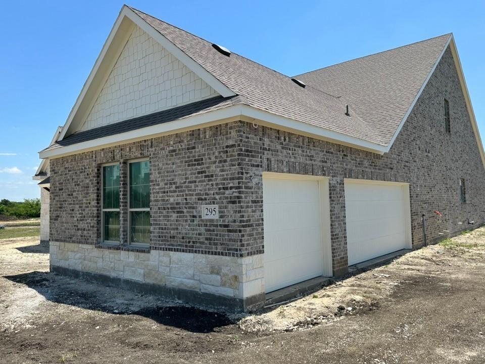 295 Brown Road Leonard, TX 75452 - Photo 3 of 26 Exterior featuring brick and stone veneer, two garage doors, dual pane windows, and an asphalt shingle roof