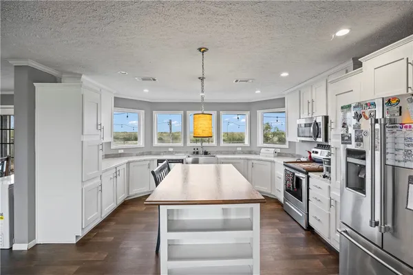 a kitchen with stainless steel appliances granite countertop a stove top oven a sink a dining table and chairs