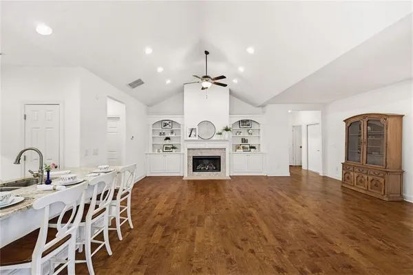 a dining area with stainless steel appliances kitchen island granite countertop a dining table chairs and a refrigerator