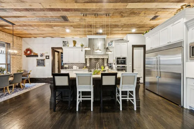 a dining room with stainless steel appliances kitchen island granite countertop a dining table chairs and granite counter tops