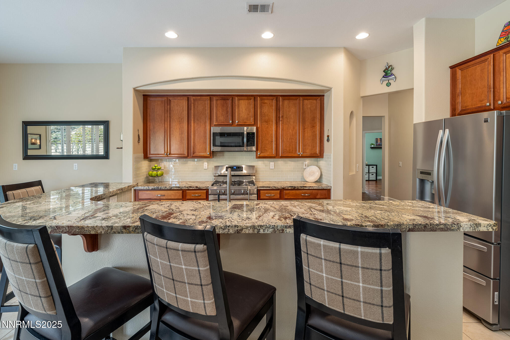 10600 Blue Moon Court Reno, NV 89521 - Photo 7 of 36 a kitchen with stainless steel appliances granite countertop a table chairs sink refrigerator and cabinets