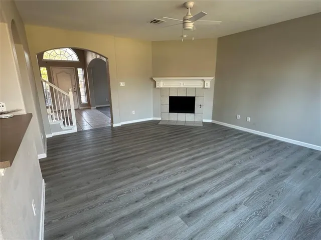 an empty room with wooden floor fireplace and windows