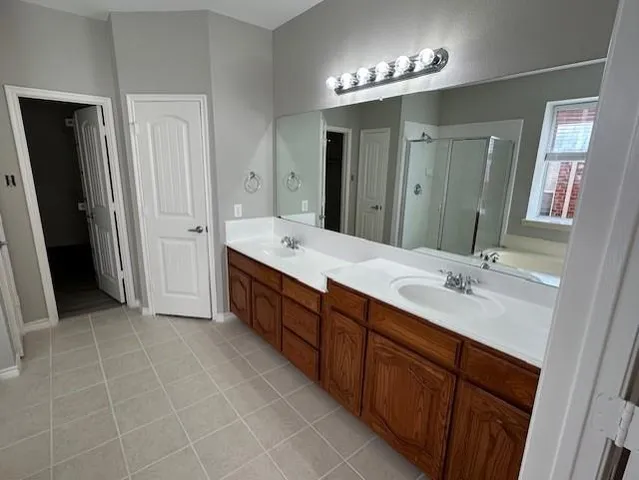 a spacious bathroom with a double vanity sink a large mirror and a shower