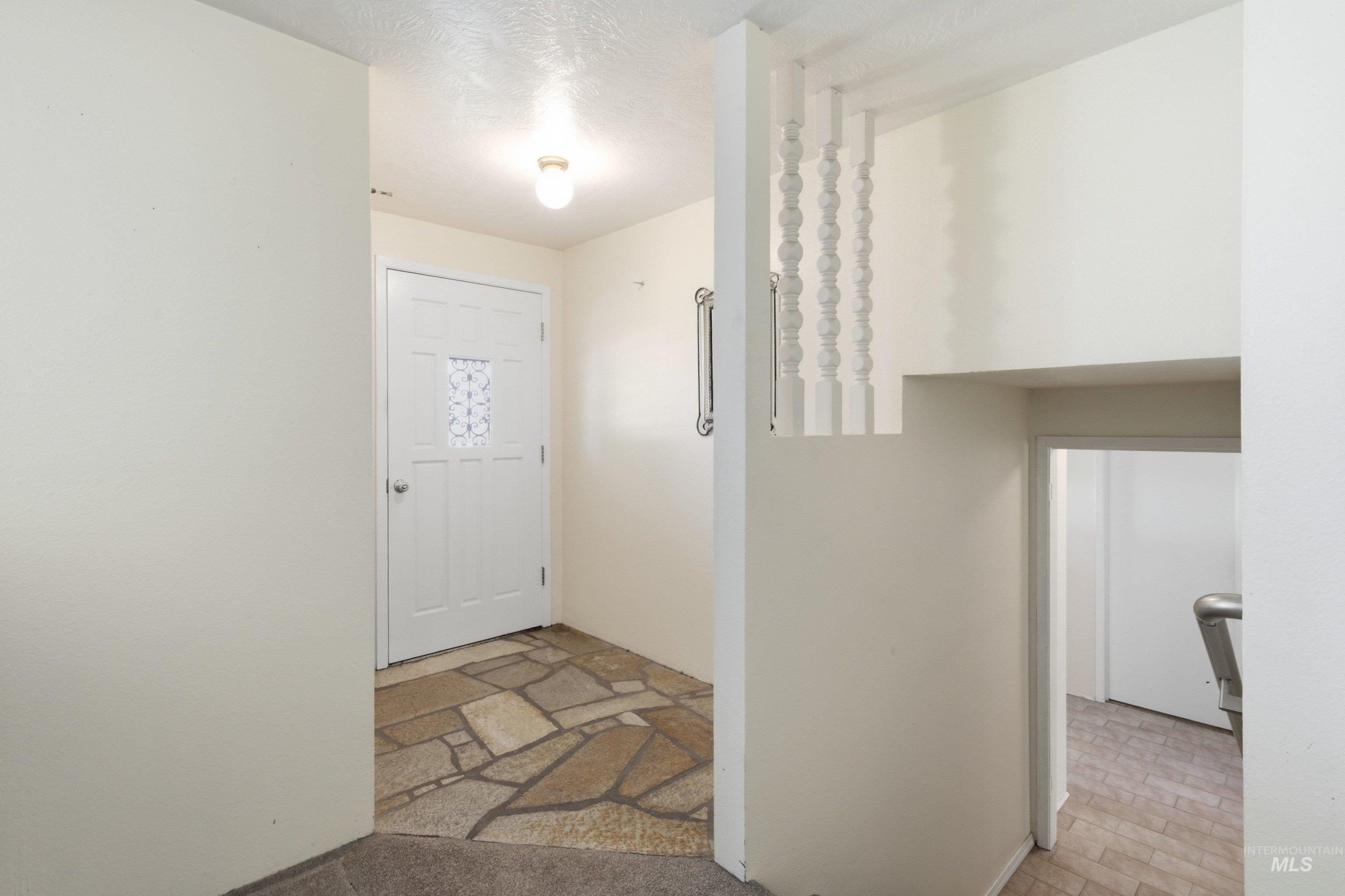 15095 David Street Caldwell, ID 83607 - Photo 8 of 39 Entryway featuring a white paneled door with decorative glass inserts, flagstone flooring, and a flush-mount ceiling light fixture