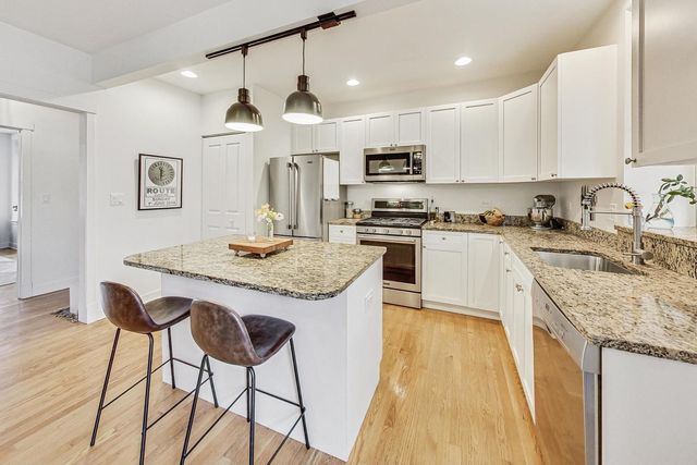 a kitchen with stainless steel appliances granite countertop a kitchen island hardwood floor sink stove and refrigerator